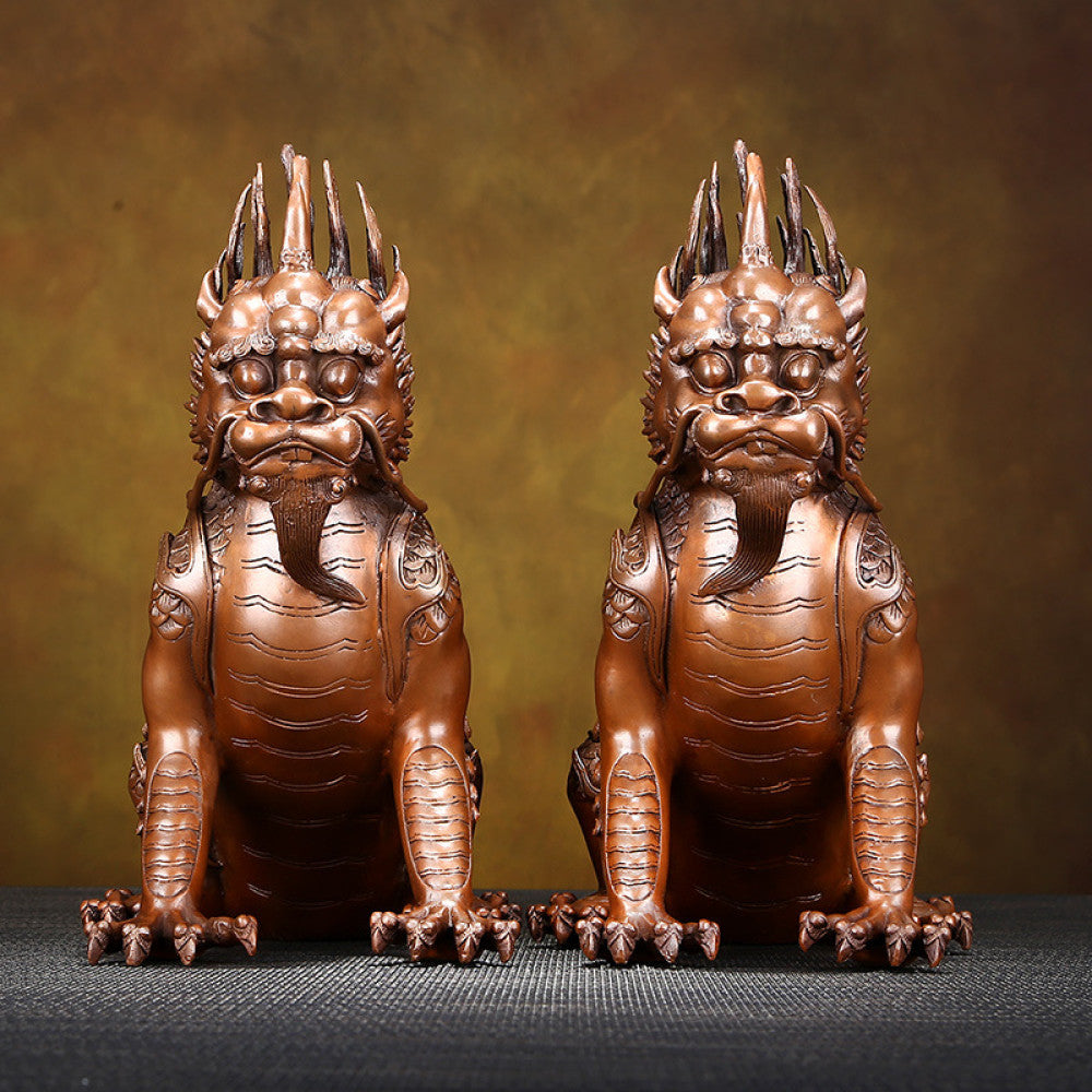Pair of traditional Chinese bronze Qilin statues with intricate carvings, displayed on a dark textured surface against a warm brown background