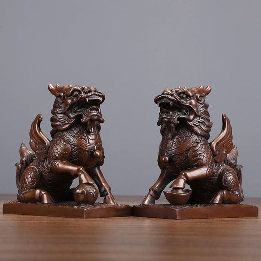 Pair of traditional Chinese bronze Qilin statues, one with a ball and one with a yuanbao ingot, placed on wooden bases against a gray background