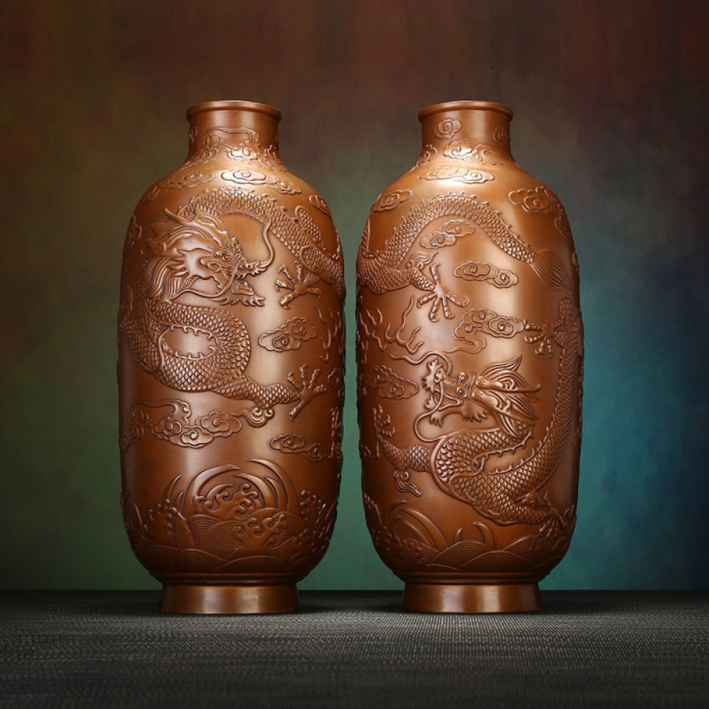 Pair of traditional Chinese bronze vases with intricate dragon carvings against a textured dark background