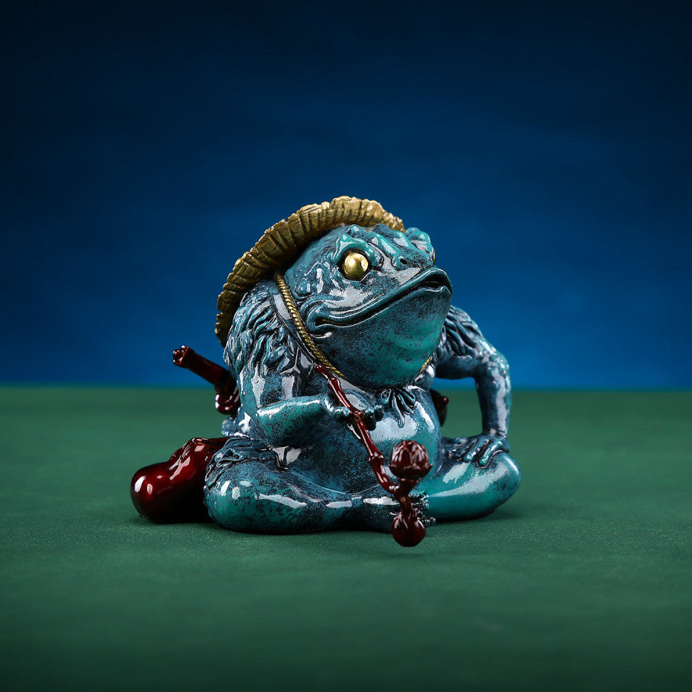 Colorful Chinese money toad statue with a straw hat, holding a ruyi - like ornament, placed on a green surface against a dark background 02