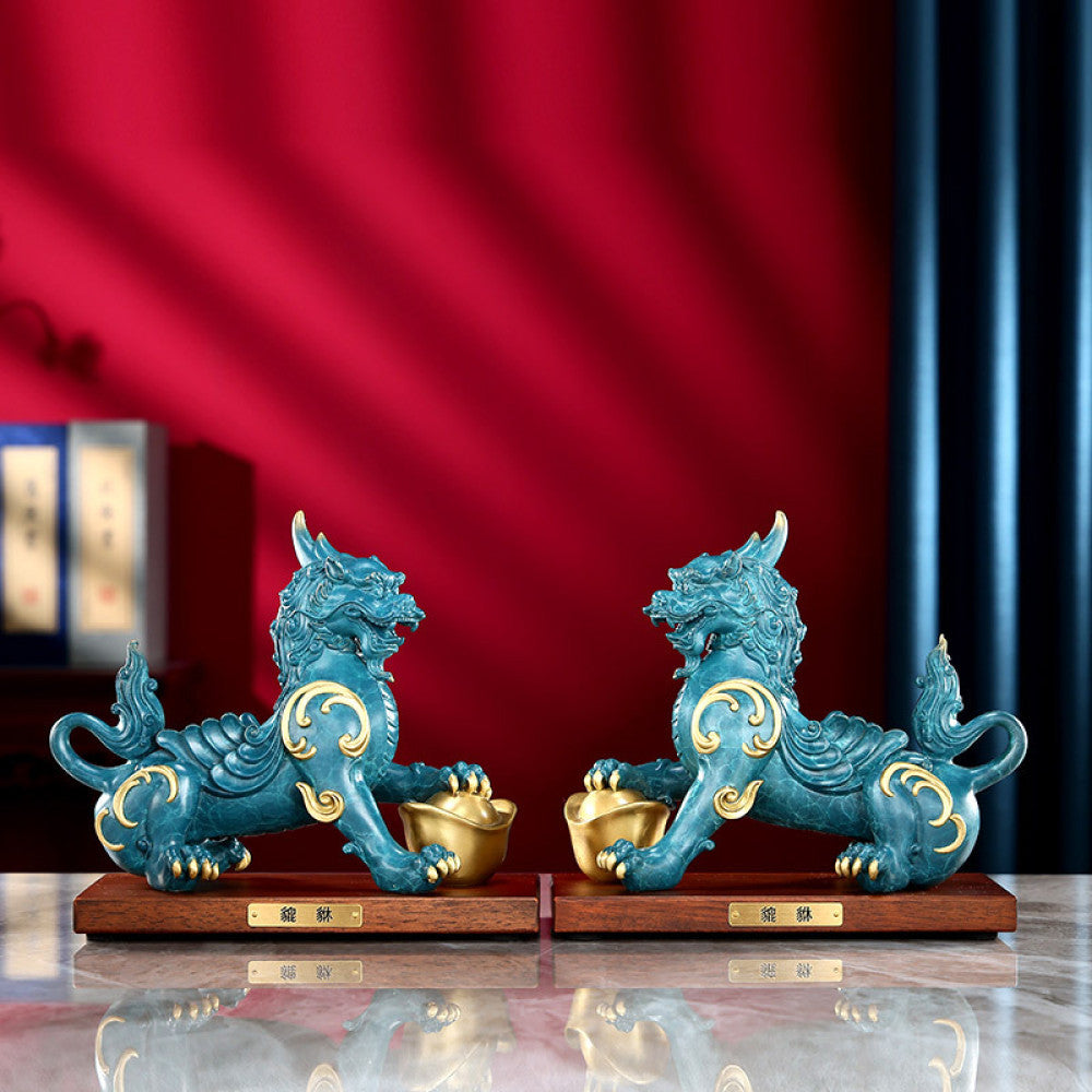 Pair of traditional Chinese Pi Xiu statues with gold inlay, holding gold ingots, placed on wooden bases against a red background