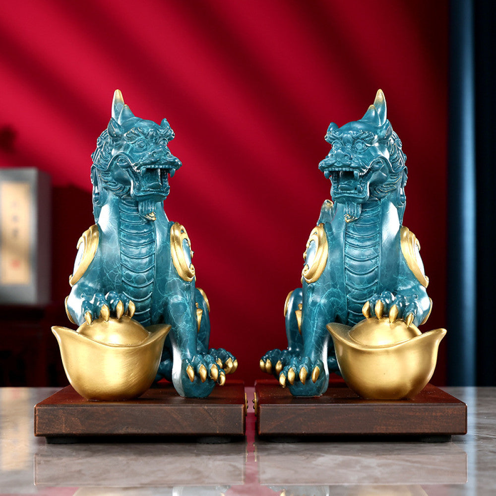 Pair of traditional Chinese Pi Xiu statues with gold inlay, holding gold ingots, placed on wooden bases against a red background 02