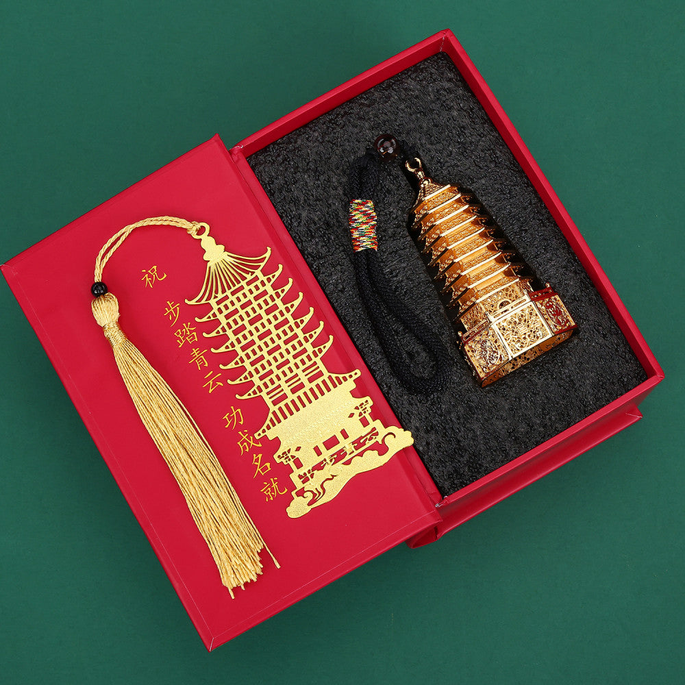 Traditional Chinese Wenchang Tower gift set with golden pendant and bookmark, presented in a red box with black cushioning, against a green background