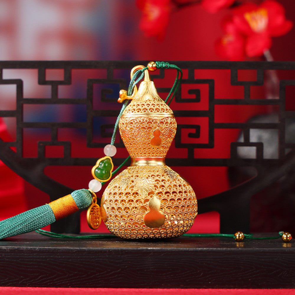 Traditional Chinese golden gourd hanging ornament with intricate openwork, tassel, and jade accents, set against a red background with Chinese lattice design