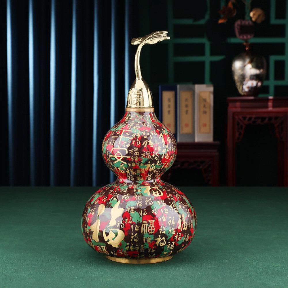 Colorful enameled Chinese gourd decoration with golden accents, placed on green surface in traditional interior setting