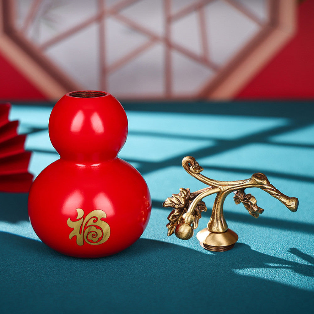 Traditional Chinese red gourd ornament with golden "Fu" character and vine details, placed on a teal surface with a red fan and lattice window in the background 01