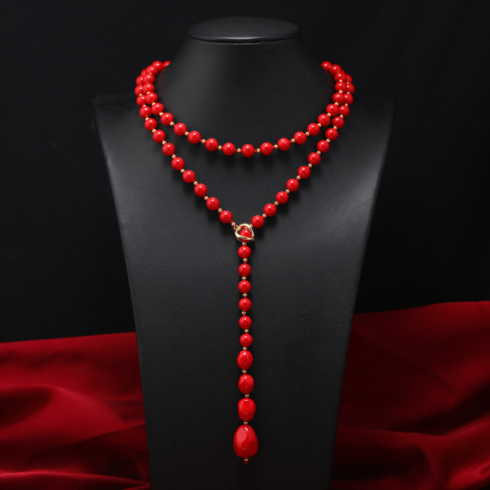Elegant multi-colored pearl Y-necklace with gold floral accent, featuring layered strands and a drop pendant, ideal for vintage-inspired formal or special occasion wear, displayed on a black mannequin against a red fabric background 01
