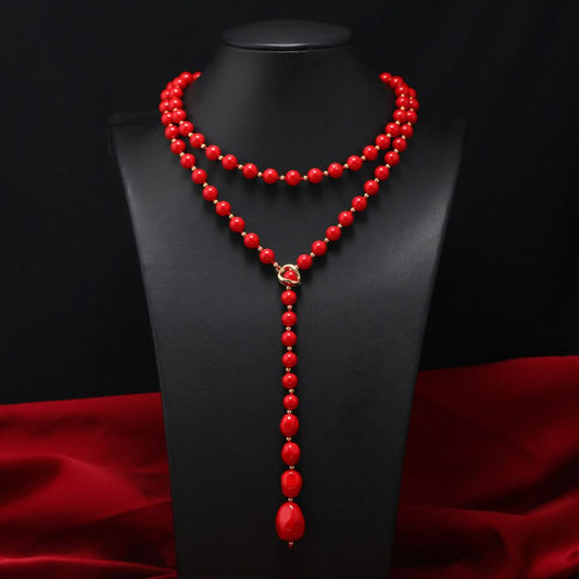 Elegant multi-colored pearl Y-necklace with gold floral accent, featuring layered strands and a drop pendant, ideal for vintage-inspired formal or special occasion wear, displayed on a black mannequin against a red fabric background 01