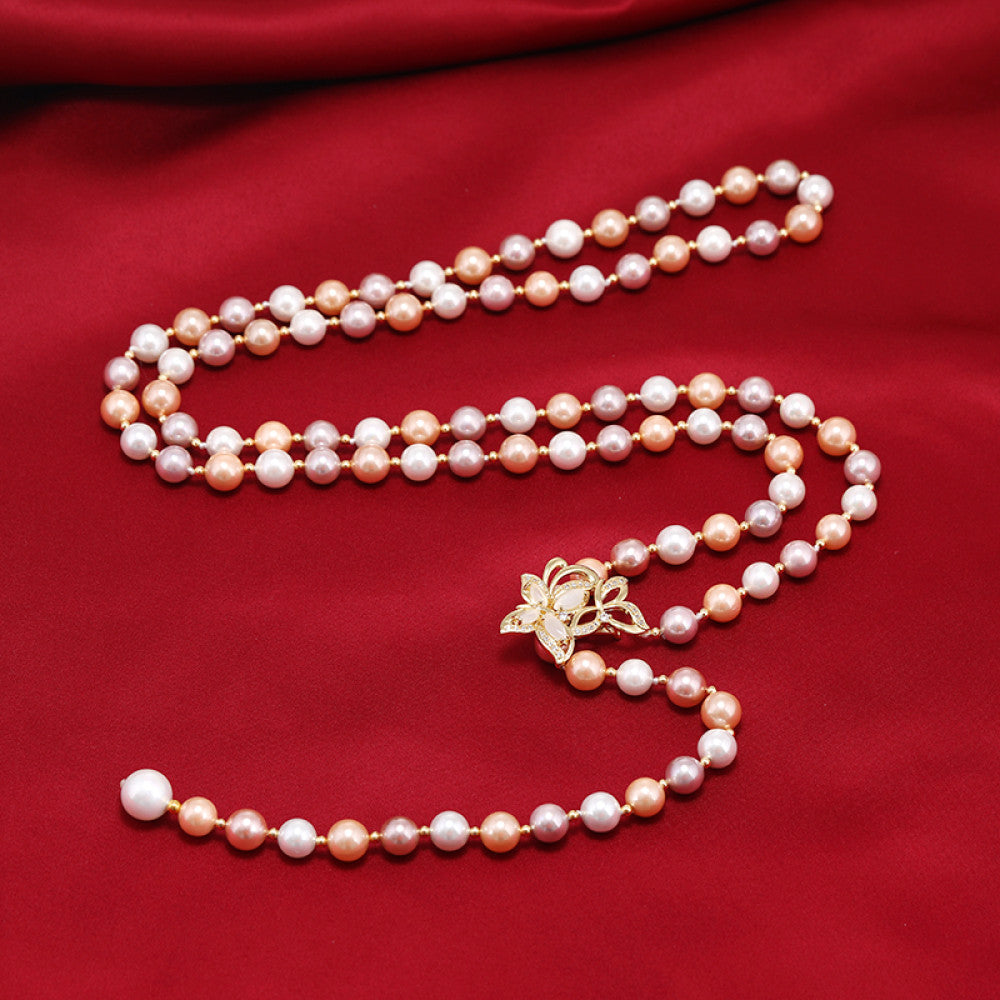 Elegant multi-colored pearl Y-necklace with gold floral accent, featuring layered strands and a drop pendant, ideal for vintage-inspired formal or special occasion wear, displayed on a black mannequin against a red fabric background 03