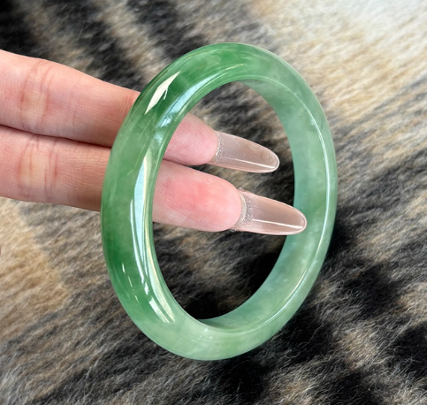 Natural bright green jadeite bangle bracelet with subtle natural patterns, held in hand to show glossy finish | DIY Jade