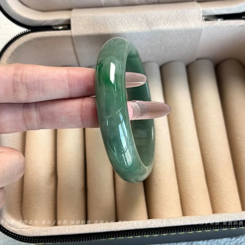 Natural dark oily green jadeite bangle held over jewelry case, showing glossy finish | DIY Jade