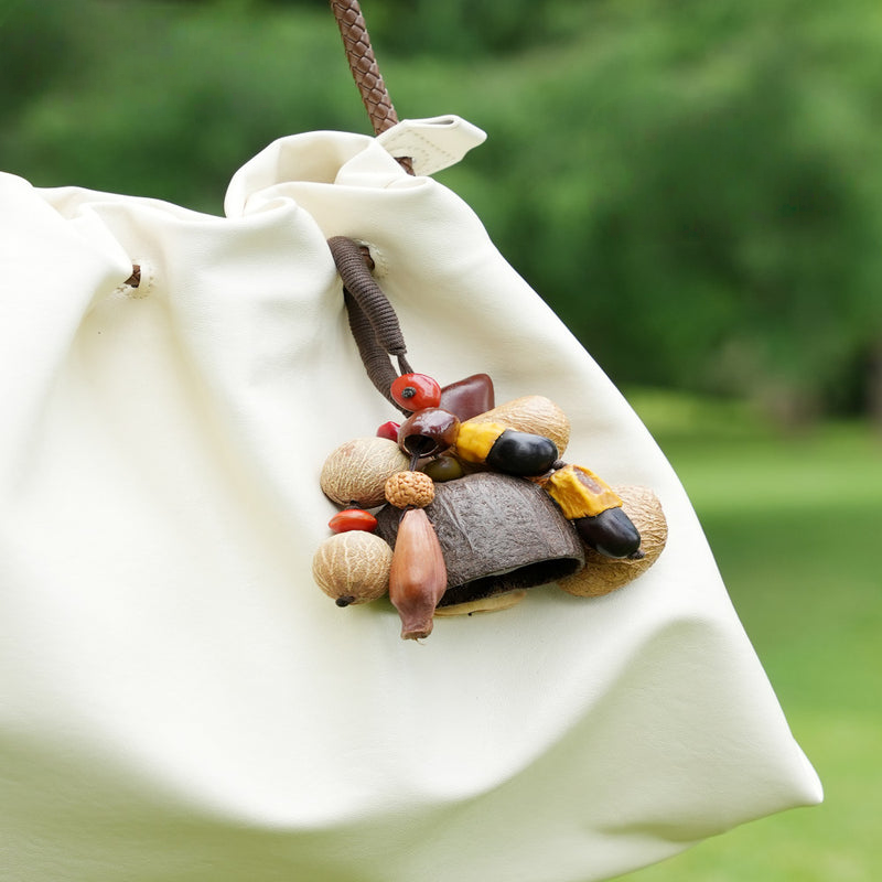 Dried nut seed pod bag charm displayed outdoors, rustic ethnic accessory on fabric pouch