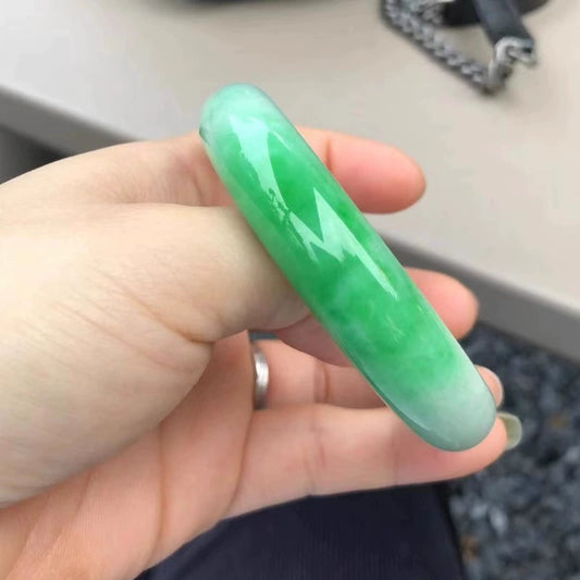 Green-white gradient jadeite bangle held in hand side view, showing smooth glossy finish | DIY Jade