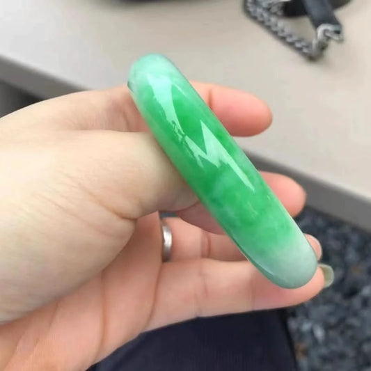 Green-white gradient jadeite bangle held in hand side view, showing smooth glossy finish | DIY Jade