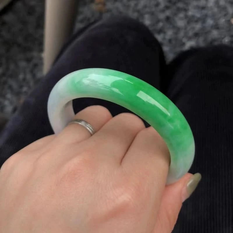 Half green half white jadeite bangle held in hand, close-up shot showing vivid green gradient | DIY Jade
