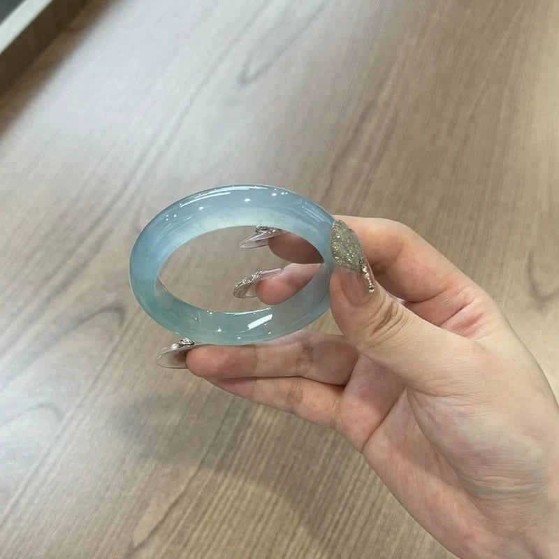 Icy blue jade bangle side view held by hand, showing smooth polished surface | DIY Jade