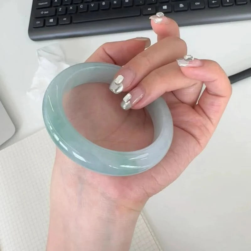 Natural icy pale green jadeite bangle held in hand at desk, everyday office lifestyle shot | DIY Jade