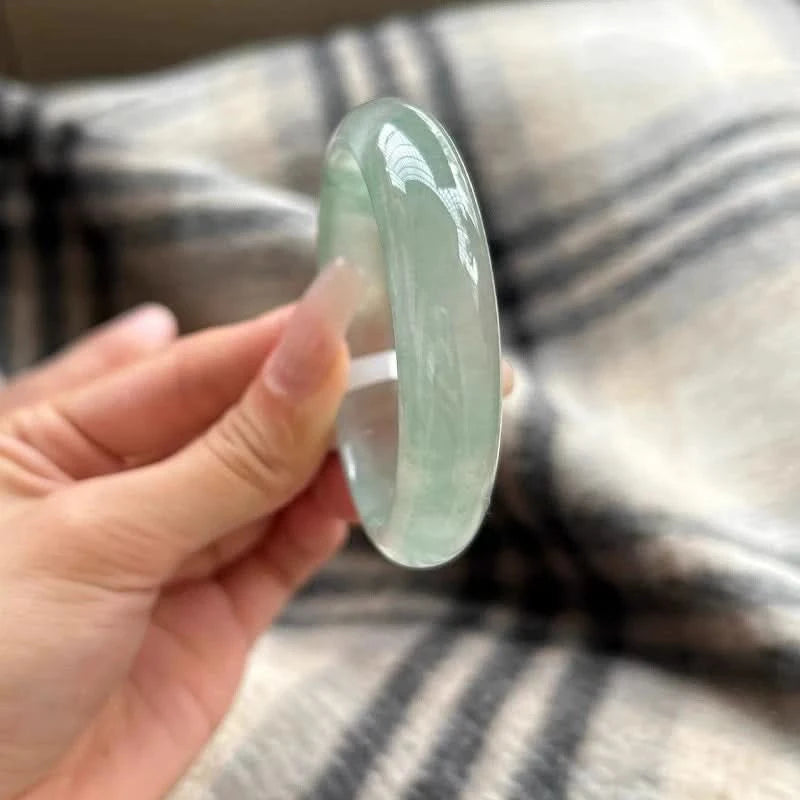 Natural icy pale green translucent jade bangle held in hand, showing smooth glossy finish | DIY Jade