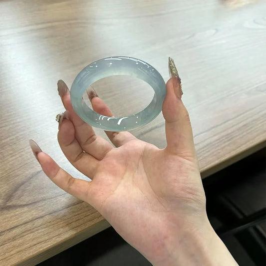 Translucent light blue jade bangle held in palm, showing round shape and glossy finish | DIY Jade