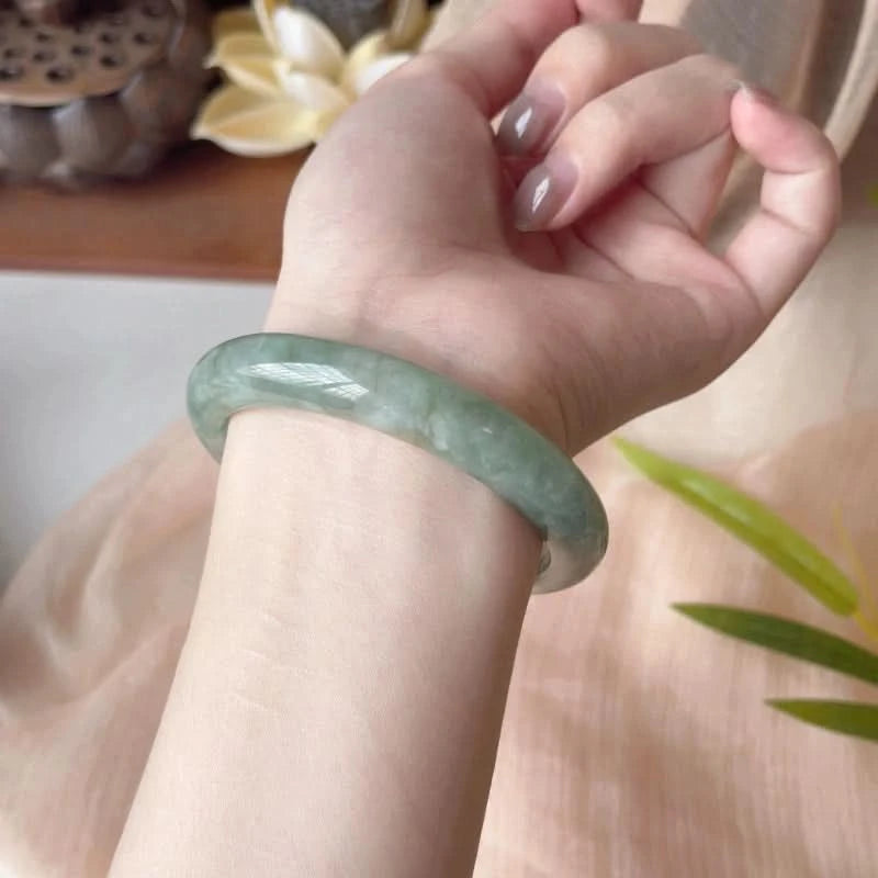 Pale green jadeite bangle bracelet worn on wrist, elegant lifestyle shot with natural decor | DIY Jade