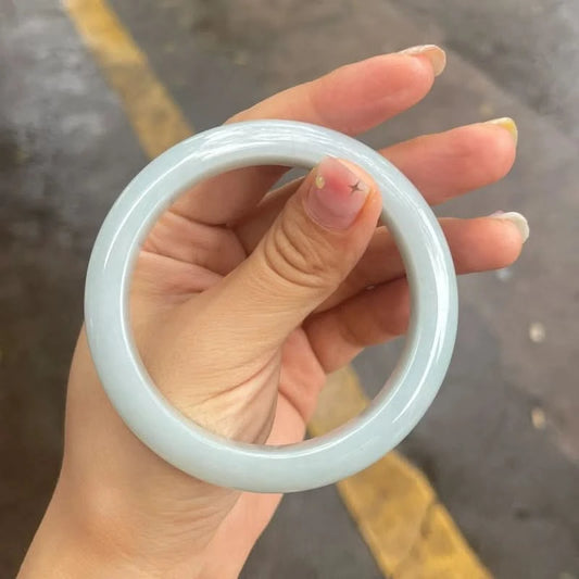 Pale white translucent jadeite bangle bracelet, held in hand to show full ring shape | DIY Jade