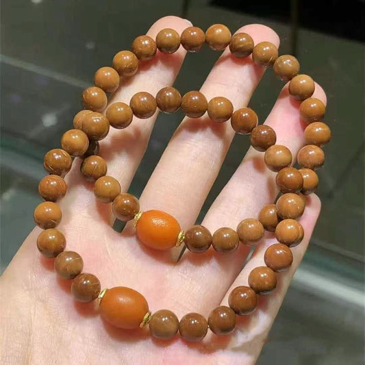 Multiple sandalwood bracelets with amber beads, stacked in hand view | DIY Jade