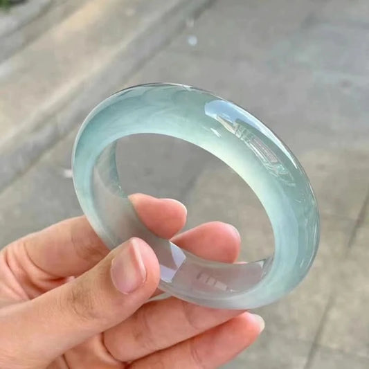 Translucent pale green jade bangle held in palm, showing elegant round shape | DIY Jade