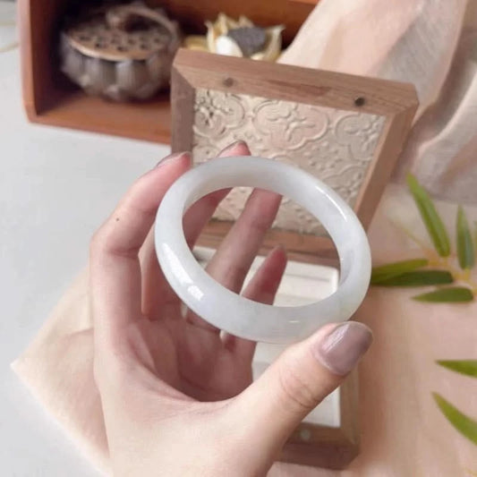 Translucent white jade bangle held in hand side view, showing elegant round shape | DIY Jade