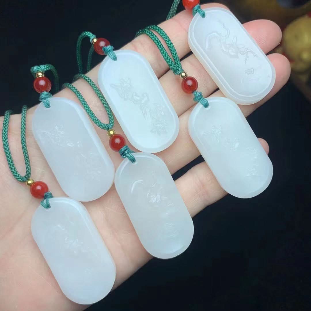 Oval white jade pendants with subtle carvings, on green cords with red beads | DIY Jade