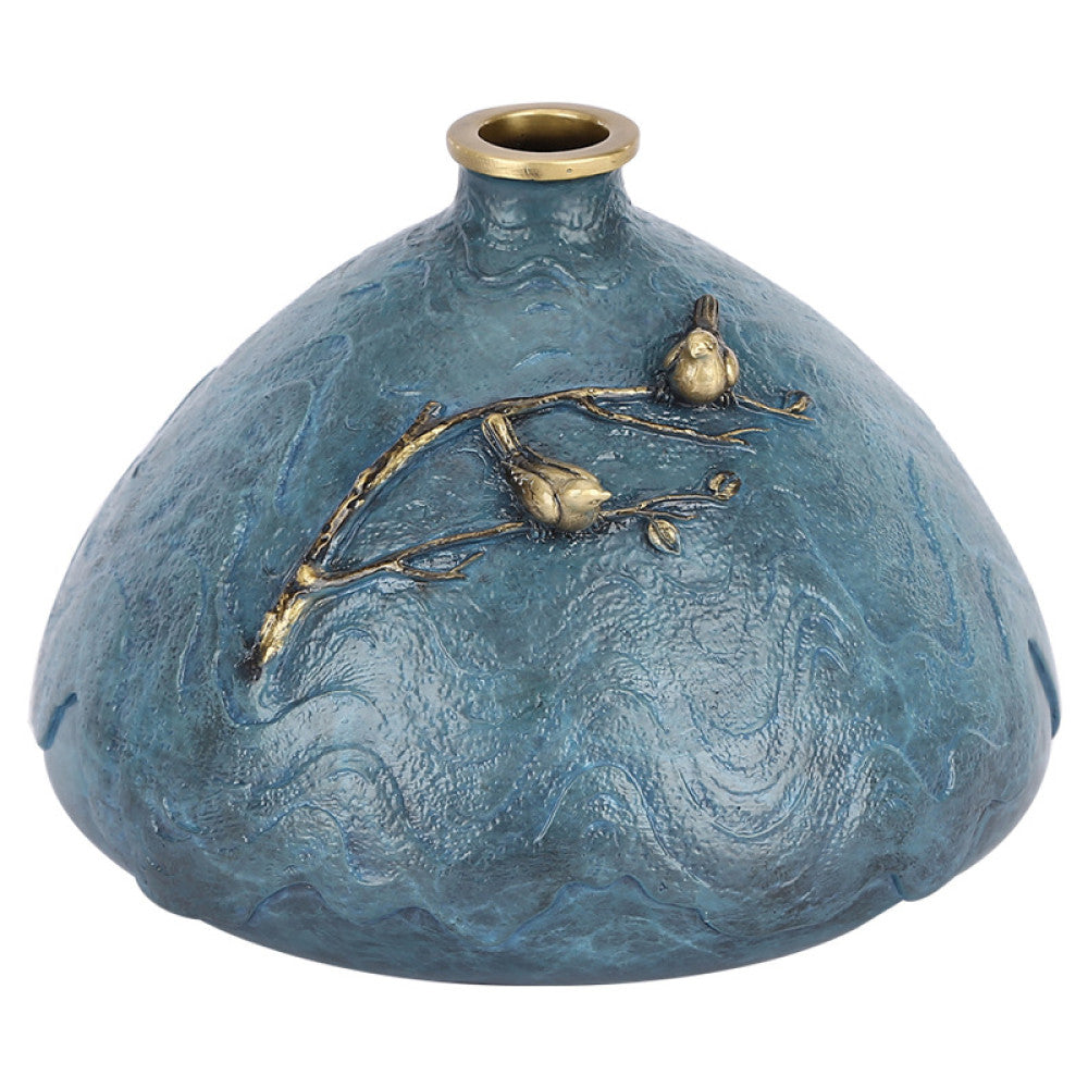 Blue textured art vase with brass branch and bird decoration against white background
