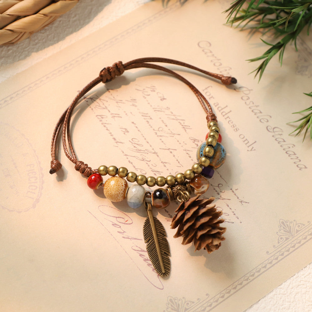 This bohemian bracelet features an adjustable brown cord, adorned with colorful beads, brass accents, and charming acorn & feather charms, bringing a whimsical, nature-inspired touch to your look 1