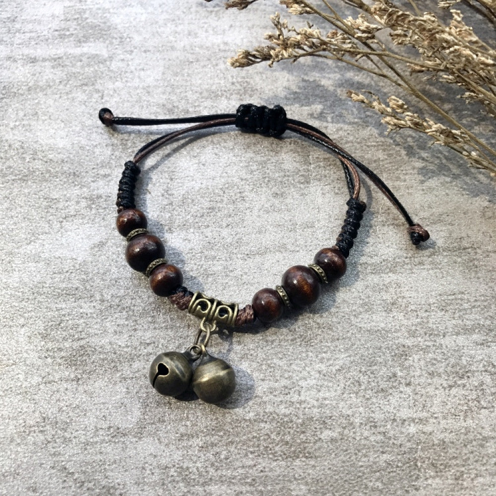 This handmade bohemian bracelet features a brown braided cord, vintage bronze bells, a star charm, and adjustable knots for a perfect fit. A unique retro accessory for daily wear 01