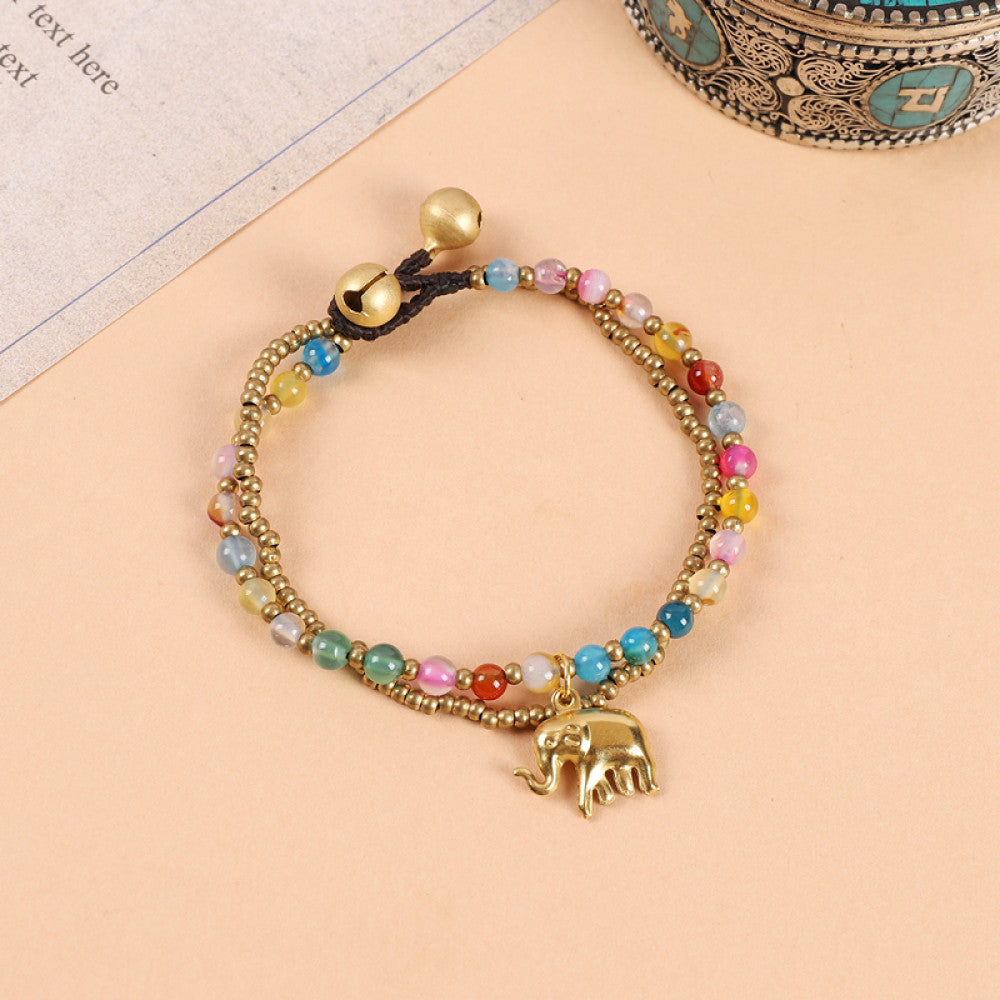 This double-layered bohemian bracelet features vibrant multicolored beads, golden bells, and a charming gold elephant charm. The adjustable knot closure ensures a perfect fit, adding a playful, ethnic-inspired touch to any outfit