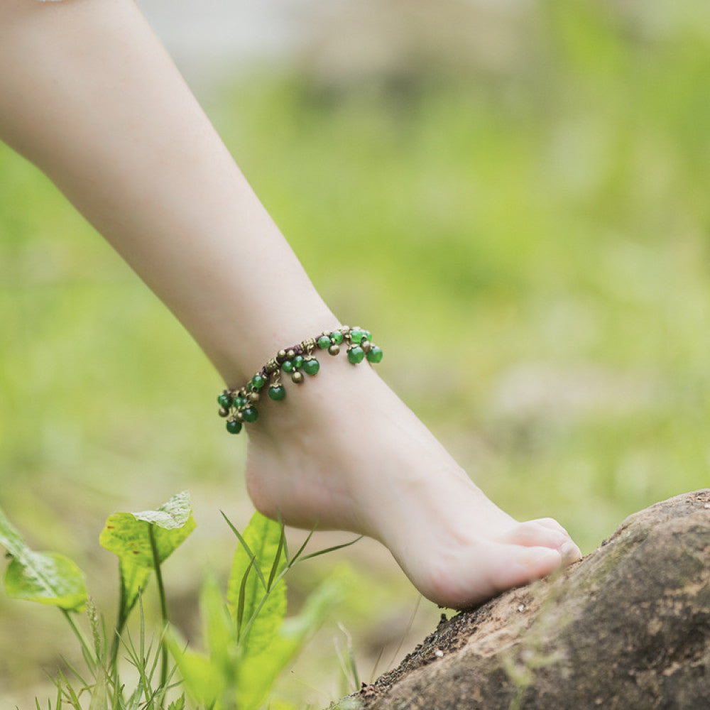 This bohemian anklet features vibrant red beads and delicate green accents on a brown cord, designed for a lightweight, nature-inspired summer look. The adjustable design ensures a comfortable fit for casual, outdoor wear 1