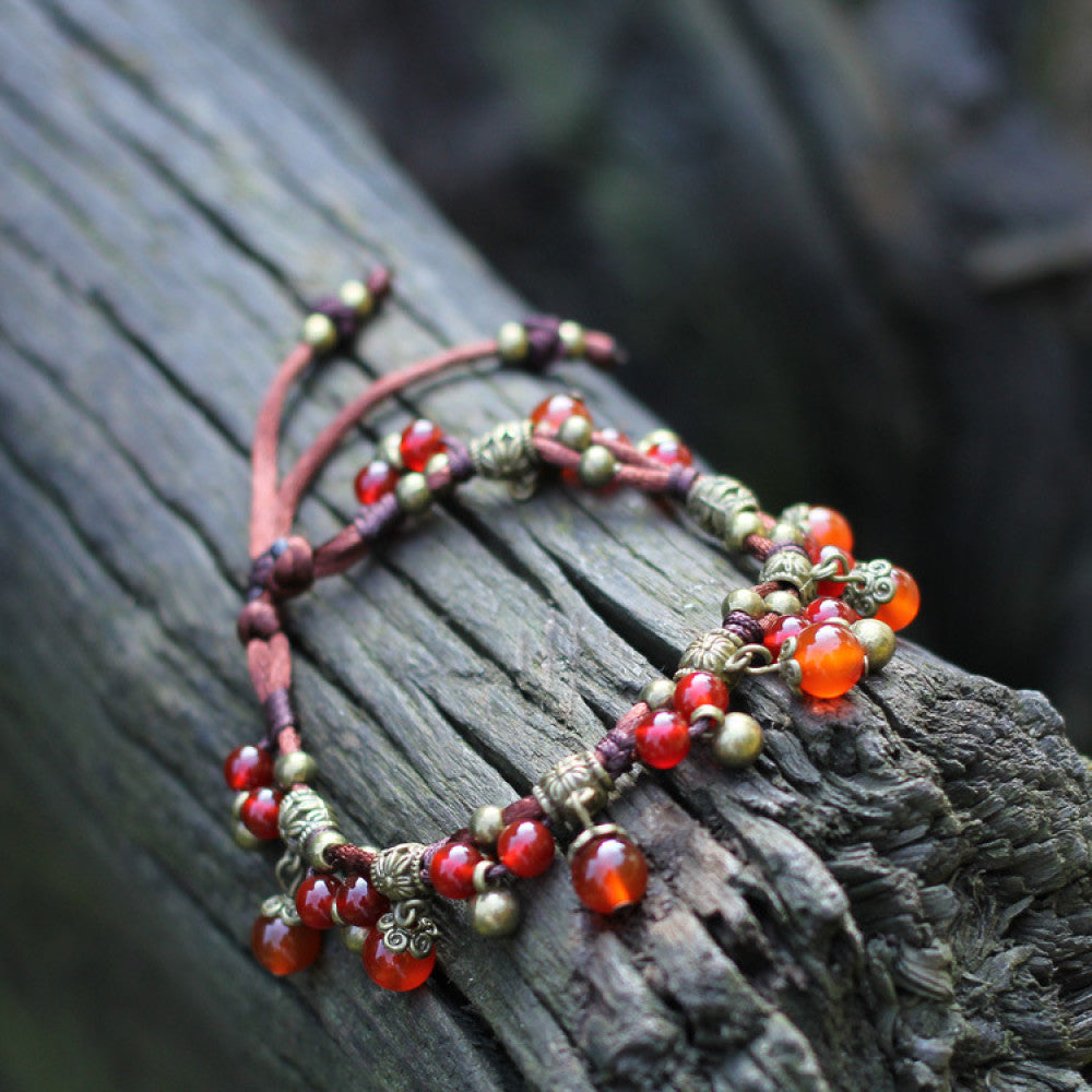 This bohemian anklet features vibrant red beads and delicate green accents on a brown cord, designed for a lightweight, nature-inspired summer look. The adjustable design ensures a comfortable fit for casual, outdoor wear 10