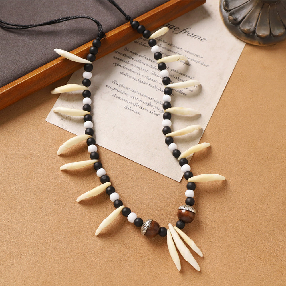 Vintage bohemian tribal necklace with bone accents, black beads, and intricate design, displayed on vintage paper, ideal for ethnic wilderness and boho fashion
