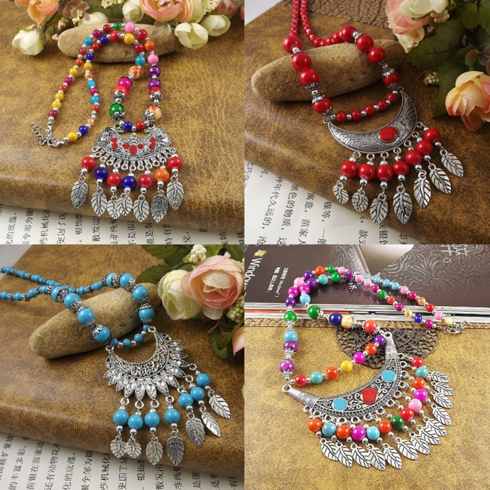 Vibrant colorful beaded necklace with intricate silver-toned leaf tassel pendant, featuring a mix of bright beads and vintage tribal design, ideal for bohemian fashion, showcased on a textured surface with floral accents
