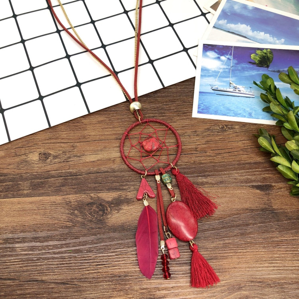 Vintage bohemian dreamcatcher necklace with feather, stone, and tassel accents, displayed on a wooden surface with grid paper and greenery, ideal for spiritual boho fashion enthusiasts 03