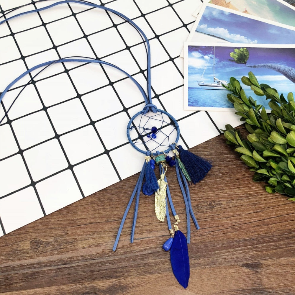 Vintage bohemian dreamcatcher necklace with feather, stone, and tassel accents, displayed on a wooden surface with grid paper and greenery, ideal for spiritual boho fashion enthusiasts 06
