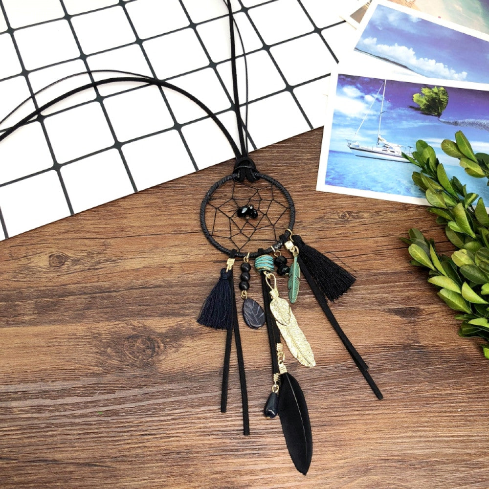 Vintage bohemian dreamcatcher necklace with feather, stone, and tassel accents, displayed on a wooden surface with grid paper and greenery, ideal for spiritual boho fashion enthusiasts 07