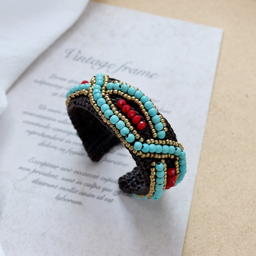 Vintage bohemian ethnic beaded cuff bracelet with turquoise and red beads, woven design, displayed on vintage paper, ideal for boho fashion enthusiasts