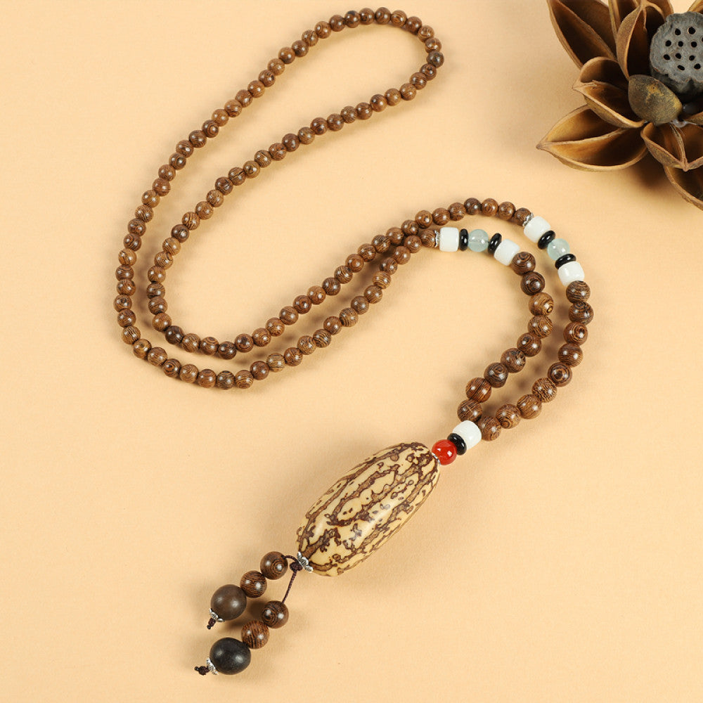 Vintage bohemian ethnic beaded necklace with intricate seed pendant and multi-color beads, ideal for spiritual boho fashion, displayed with a decorative flower against a neutral background