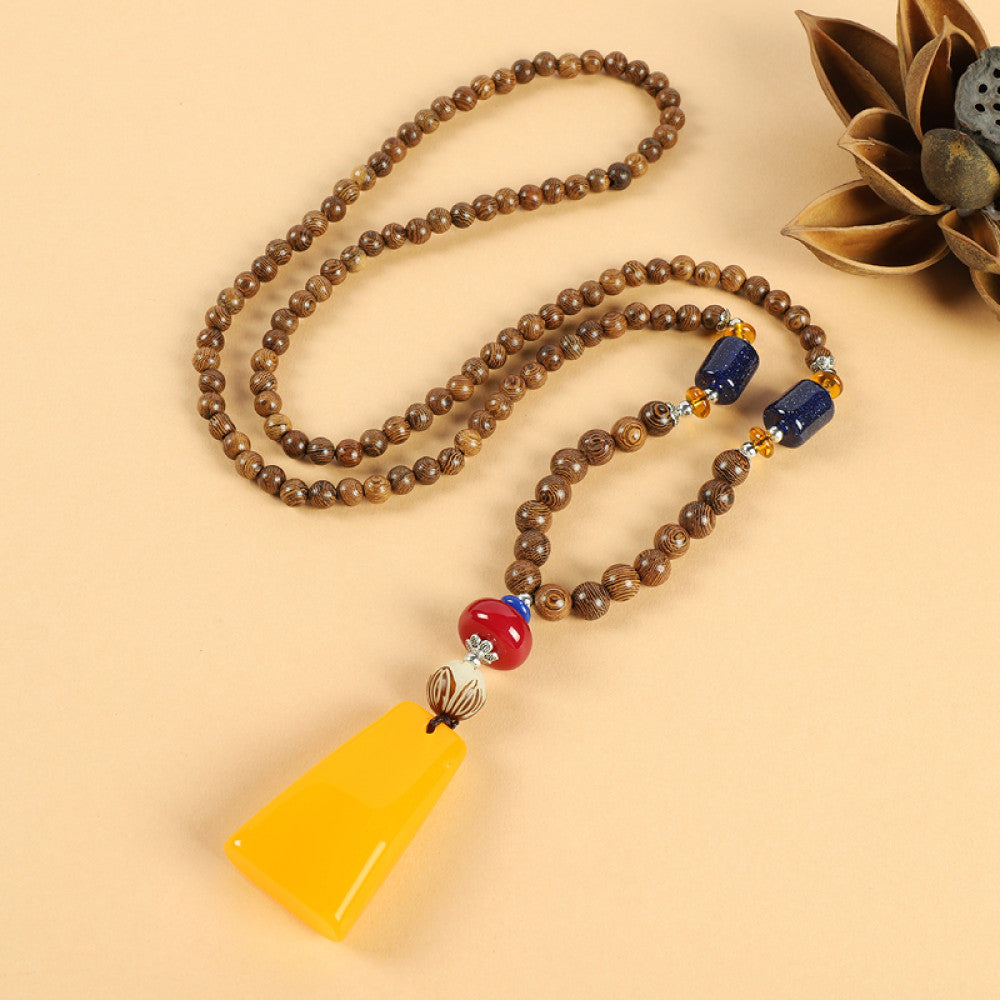 Vintage bohemian ethnic beaded necklace with intricate seed pendant and multi-color beads, ideal for spiritual boho fashion, displayed with a decorative flower against a neutral background 02