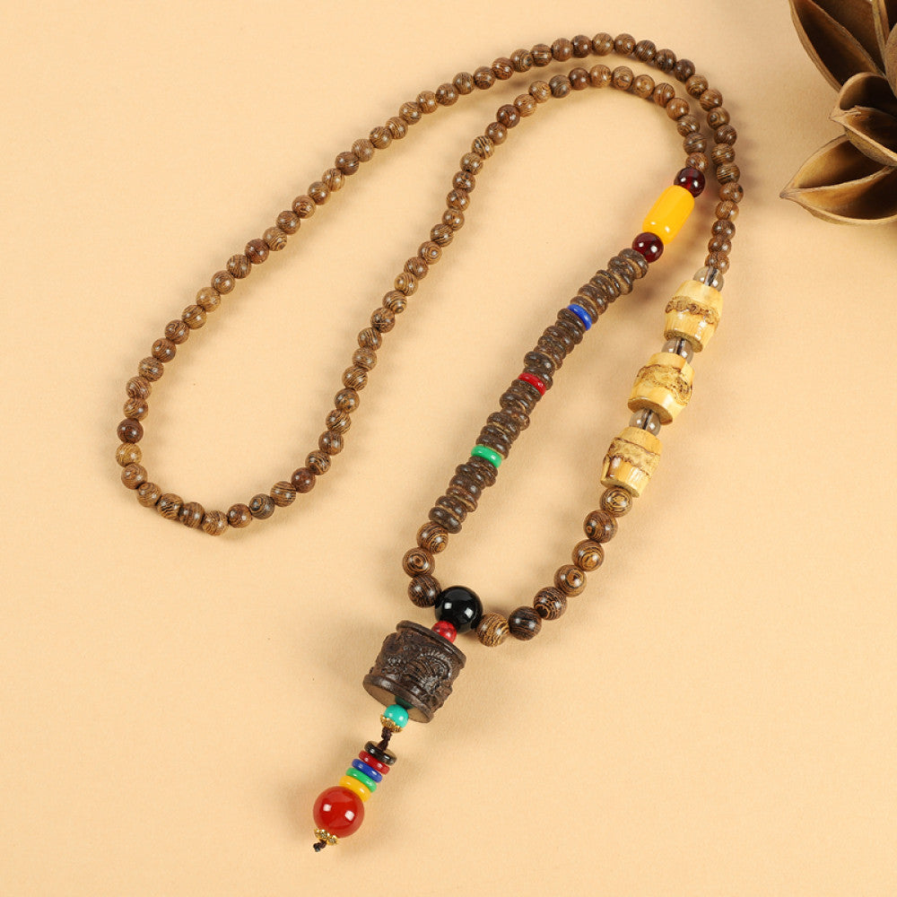 Vintage bohemian ethnic beaded necklace with intricate seed pendant and multi-color beads, ideal for spiritual boho fashion, displayed with a decorative flower against a neutral background 04
