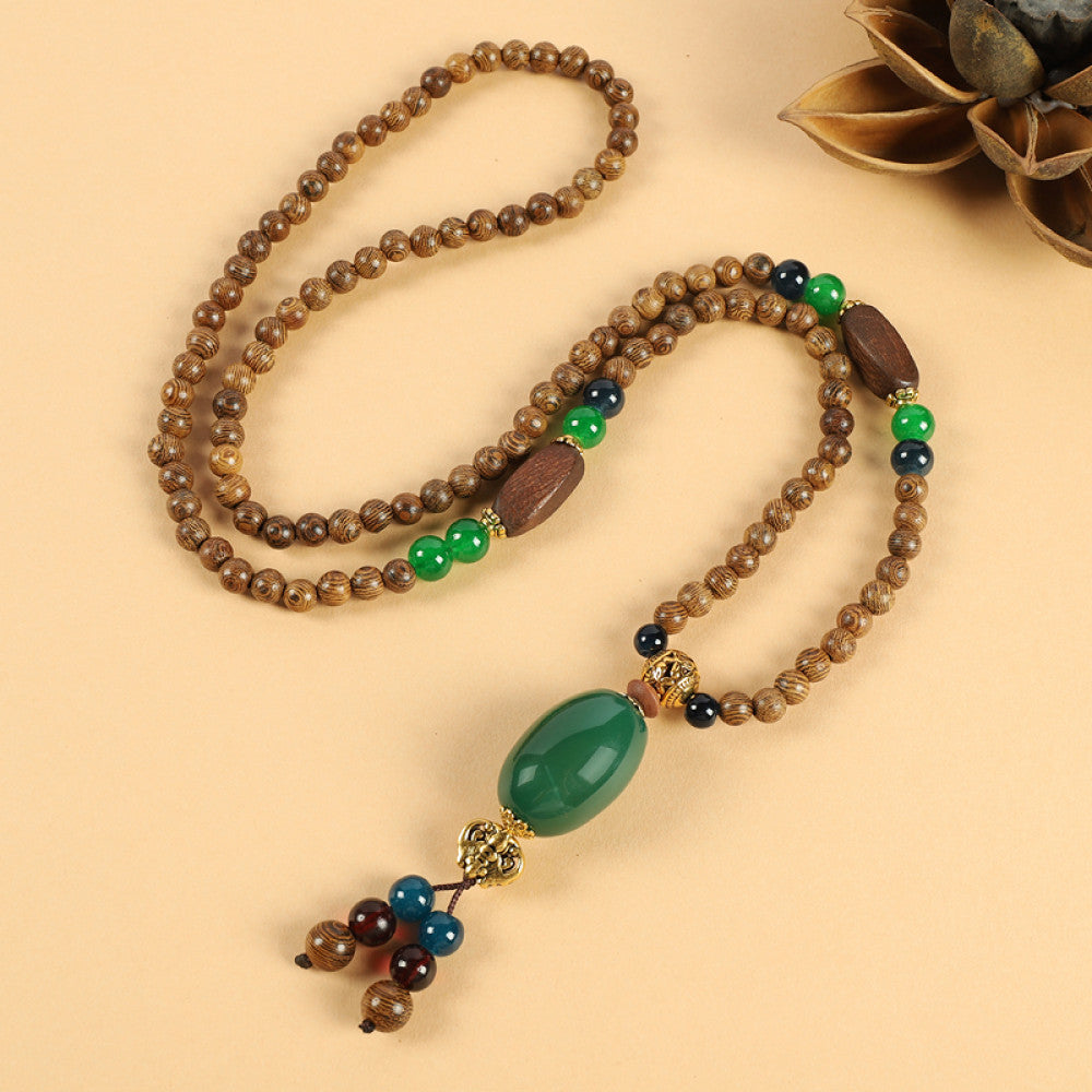 Vintage bohemian ethnic beaded necklace with intricate seed pendant and multi-color beads, ideal for spiritual boho fashion, displayed with a decorative flower against a neutral background 06