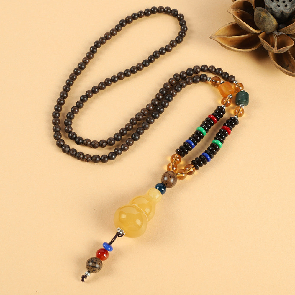 Vintage bohemian ethnic beaded necklace with intricate seed pendant and multi-color beads, ideal for spiritual boho fashion, displayed with a decorative flower against a neutral background 07