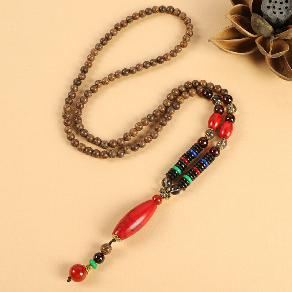 Vintage bohemian ethnic beaded necklace with red pendant and multi-color beads, ideal for spiritual boho fashion, displayed with a decorative flower against a neutral background