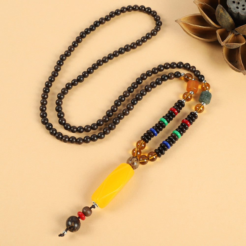 Vintage bohemian ethnic beaded necklace with red pendant and multi-color beads, ideal for spiritual boho fashion, displayed with a decorative flower against a neutral background 03