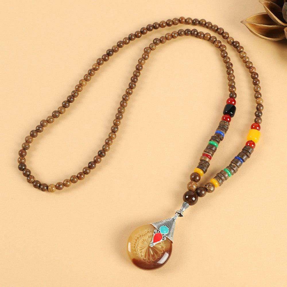 Vintage bohemian ethnic beaded necklace with red pendant and multi-color beads, ideal for spiritual boho fashion, displayed with a decorative flower against a neutral background 05