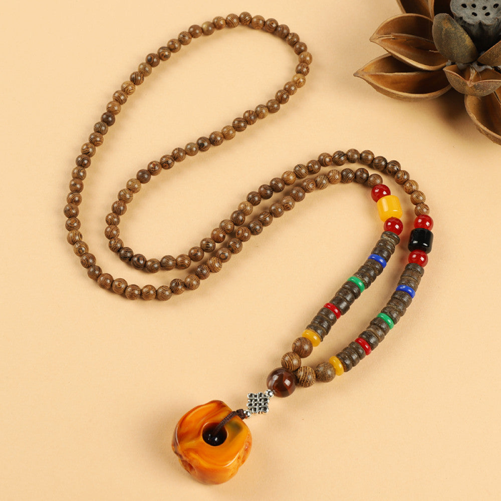 Vintage bohemian ethnic beaded necklace with red pendant and multi-color beads, ideal for spiritual boho fashion, displayed with a decorative flower against a neutral background 9